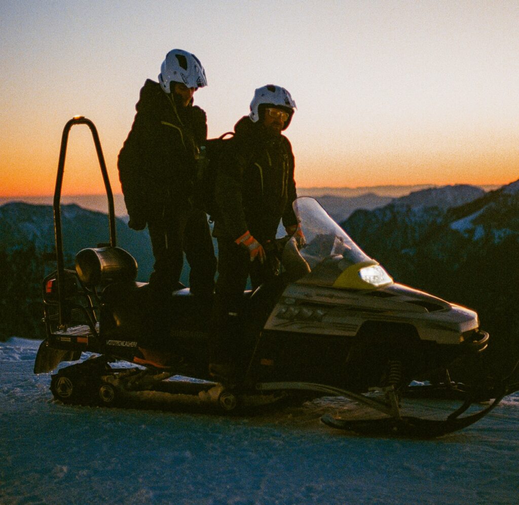 Attività all'aperto : due partecipanti a un’escursione in motoslitta tra le montagne della Val Brembana, con vista al tramonto