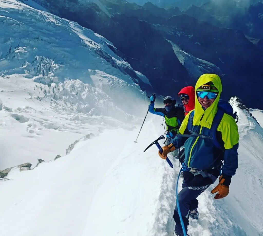 Gruppo di alpinisti in cordata su una cresta innevata nelle Orobie, accompagnati da guida alpina