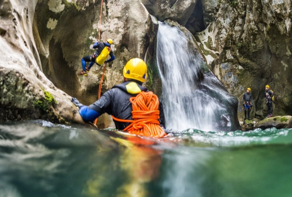 Escursionisti con mute e caschi durante un’uscita di canyoning tra cascate e gole rocciose